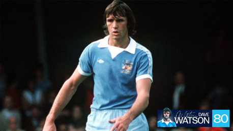 A football player in a vintage Manchester City kit, wearing a sky-blue jersey with a white collar and shorts. The image has a header including 'Dave Watson' and the number '80'.