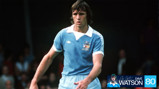 A football player in a vintage Manchester City kit, wearing a sky-blue jersey with a white collar and shorts. The image has a header including 'Dave Watson' and the number '80'.