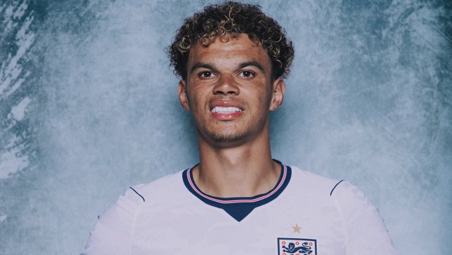 A person wearing an England football jersey with a blurred face on a textured blue-grey background.