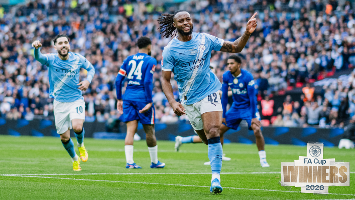 Manchester City players celebrating on the field wearing their light blue kit after winning the FA Cup 2026, with Manchester City’s logo and 'FA Cup Winners 2026' displayed in the corner.
