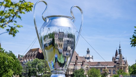 A large replica of the UEFA Champions League trophy set outdoors against a backdrop of historic architecture.