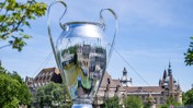 A large replica of the UEFA Champions League trophy set outdoors against a backdrop of historic architecture.
