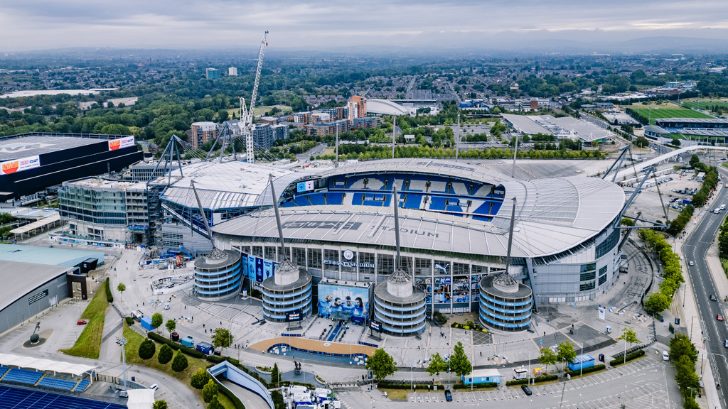Aerial view of Etihad Stadium, home of Manchester City Football Club, showing surrounding areas and ongoing construction.