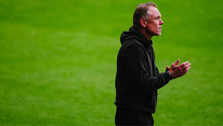 Person in black clothing clapping on a grass field, face blurred.