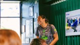A person wearing a Manchester City shirt is laughing during a presentation. There is a screen displaying a slide titled 'PEP TALK.'