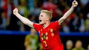 A football player in a red Belgium national team jersey with number 7 is celebrating with raised arms during a match.