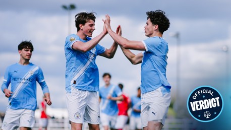 Football players in Manchester City jerseys celebrate by high-fiving on the field. The image includes logos for Manchester City and Puma.