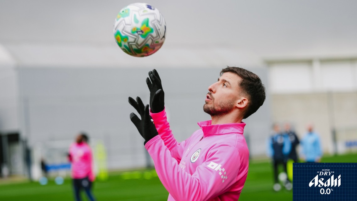 A player in a pink Manchester City training kit attempts to control a soccer ball during a practice session outdoors.