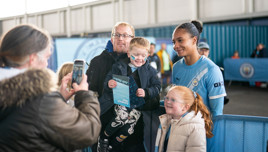Family and Manchester City team member posing for photo at a mascot event at the Joie Stadium.