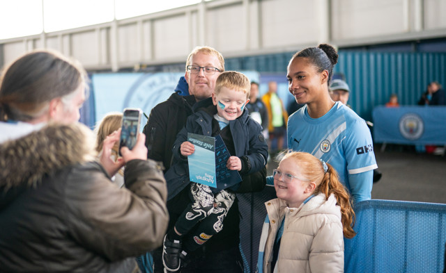 Family and Manchester City team member posing for photo at a mascot event at the Joie Stadium.