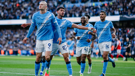 Players in Manchester City jerseys celebrate a goal on the field during a match.