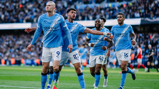 Players in Manchester City jerseys celebrate a goal on the field during a match.