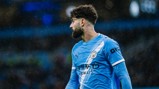 A Manchester City player in a blue and white striped jersey during a match in the rain.