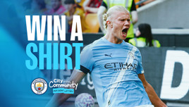 Promotional image featuring a Manchester City player in action celebrating with text 'Win a Shirt.' Manchester City and City in the Community logos are also visible.