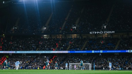 Football match at Etihad Stadium with Manchester City playing against Brighton & Hove Albion. Scoreboard shows Manchester City 1 - Brighton & Hove Albion 2 with 60:40 on the clock.