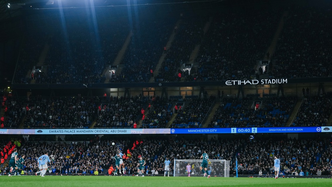 Football match at Etihad Stadium with Manchester City playing against Brighton & Hove Albion. Scoreboard shows Manchester City 1 - Brighton & Hove Albion 2 with 60:40 on the clock.