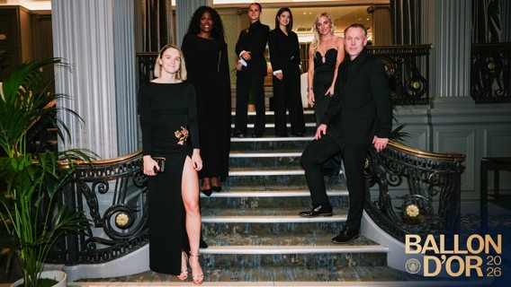 A group of six people dressed formally, standing on stairs for Ballon d'Or 2026 event.
