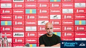A person sitting at a press conference desk with an Emirates FA Cup backdrop featuring various sponsor logos.