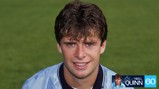 A portrait of a young man with curly hair wearing a light blue football jersey on a green field. There is a watermark with the name 'Niall Quinn' and a number '60'.