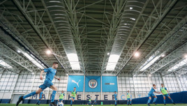 Boys playing football on an indoor pitch at Manchester City