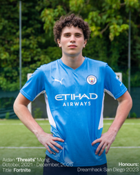 Person wearing a blue Manchester City jersey stands confidently with hands on hips. Text includes name: Aidan ‘Threats’ Mong, contract details, title: Fortnite, and honour: Dreamhack San Diego 2023.