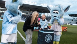 Manchester City mascots Moonbeam and Moonchester interacting with people at a stadium event.