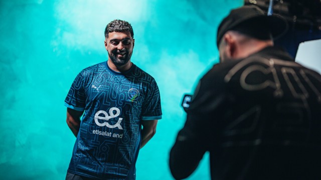 A person wearing a Manchester City Esports jersey featuring a geometric pattern with the Etisalat And sponsor logo being photographed.