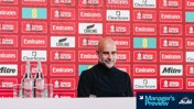A person in a dark sweater is at a press conference in front of a backdrop with FA Cup logos and sponsors like Carling and Clearscore. Bottled water is on the desk, with 'Manager's Preview' text in the corner.