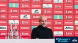A person in a dark sweater is at a press conference in front of a backdrop with FA Cup logos and sponsors like Carling and Clearscore. Bottled water is on the desk, with 'Manager's Preview' text in the corner.