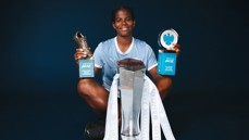 A soccer player holding Barclays WSL Golden Boot and Player of the Season trophies, Manchester City jersey, with a silver trophy in front.
