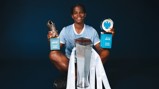 A soccer player holding Barclays WSL Golden Boot and Player of the Season trophies, Manchester City jersey, with a silver trophy in front.