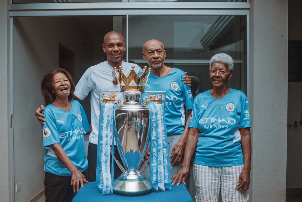 Fernandinho com seu pai e a tias ao lado do troféu conquistado pelo capitão