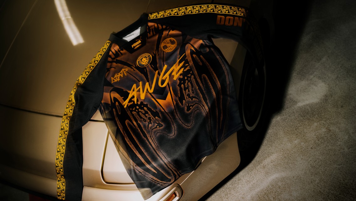 A black and gold jersey featuring graphic designs and logos, including PUMA, AWGE, and Borussia Dortmund.