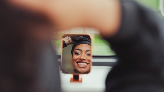 Partially blurred image focuses on a tattooed forearm reflected in a small mirror.