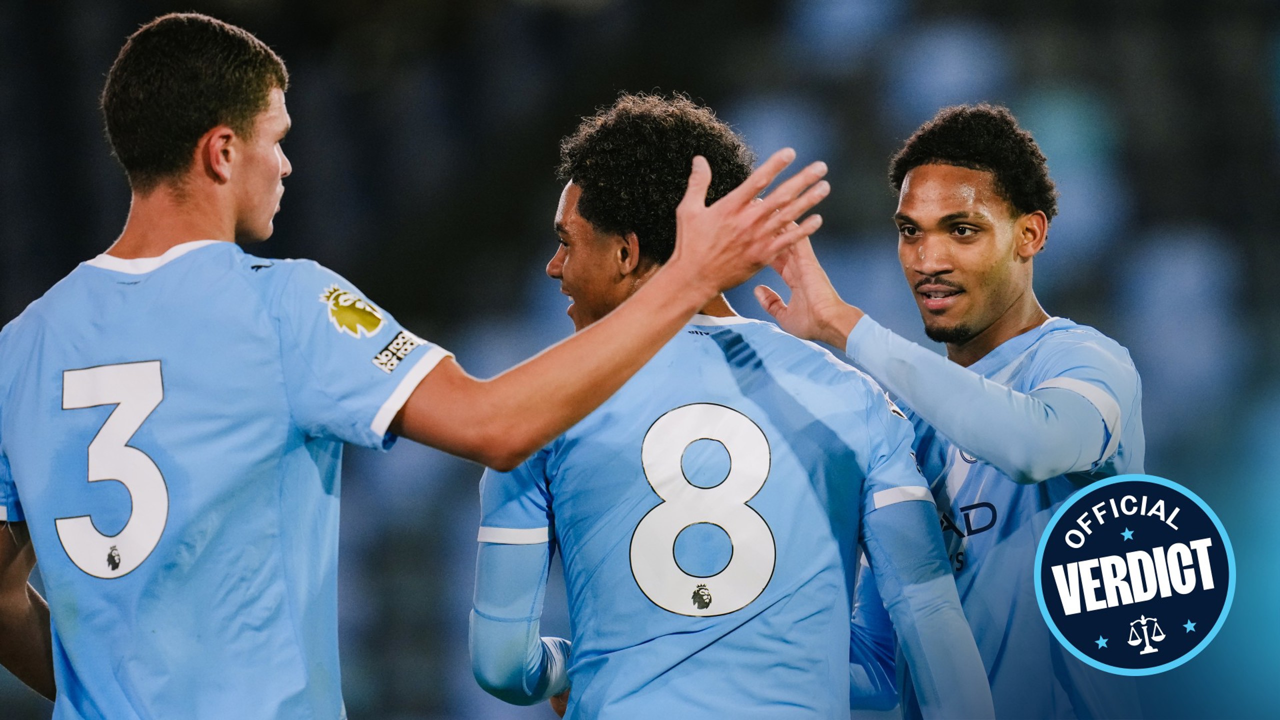 Three Manchester City players in light blue jerseys celebrating during a match with blurred faces.