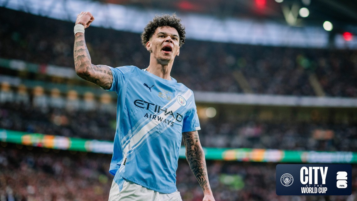 A Manchester City player in a blue jersey celebrates with a raised fist in a stadium. The jersey displays Etihad Airways as the sponsor.