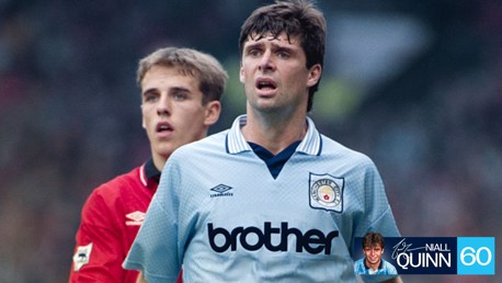 Two soccer players during a match. One wears a Manchester City jersey, and the other is wearing a red jersey, possibly representing Manchester United.