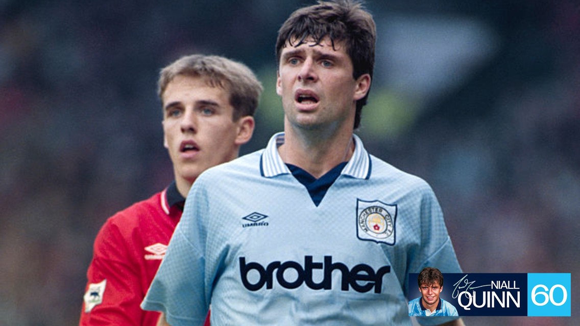 Two soccer players during a match. One wears a Manchester City jersey, and the other is wearing a red jersey, possibly representing Manchester United.