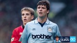 Two soccer players during a match. One wears a Manchester City jersey, and the other is wearing a red jersey, possibly representing Manchester United.