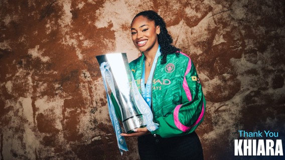 A person smiling while holding a large trophy, wearing a Manchester City jacket. The words 'Thank You Khiara' are seen on the image.