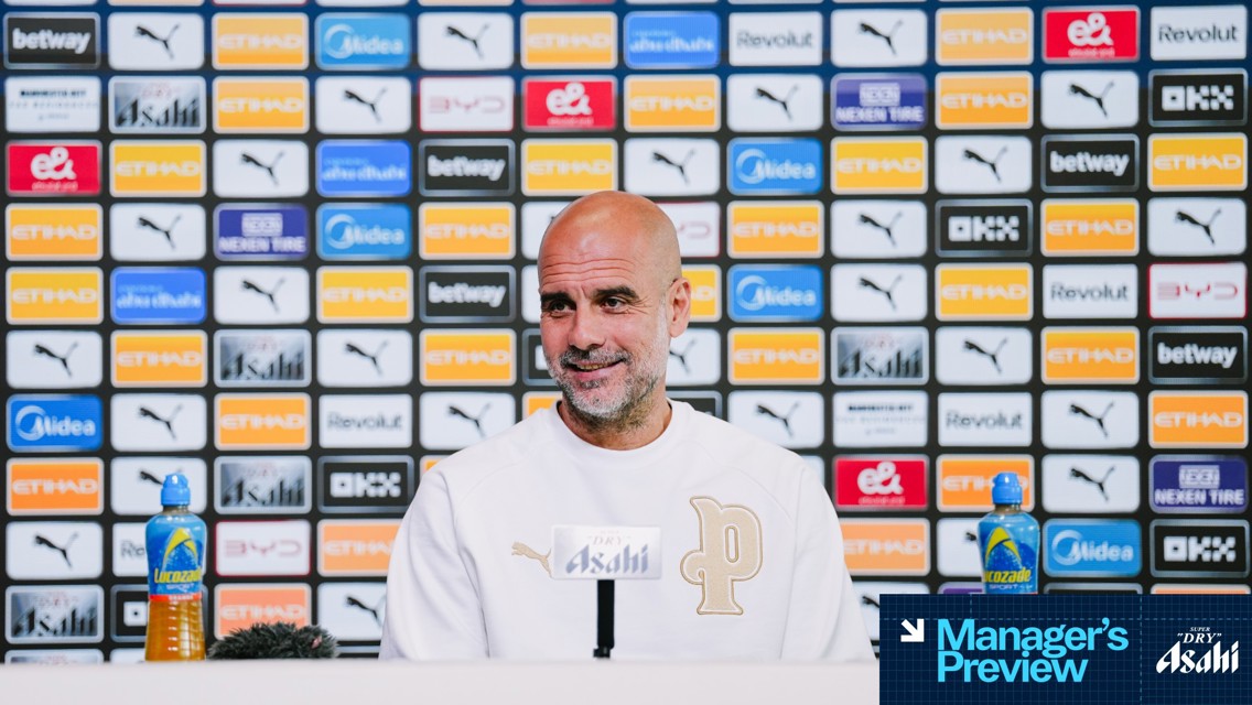 A person with blurred face is seated at a press conference with Lucozade bottles. Background displays various sponsor logos like Etihad, Puma, and Asahi. Text reads 'Manager's Preview'.