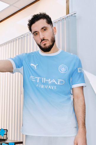 A person wearing a Manchester City football jersey with 'Etihad Airways' and Puma logos.