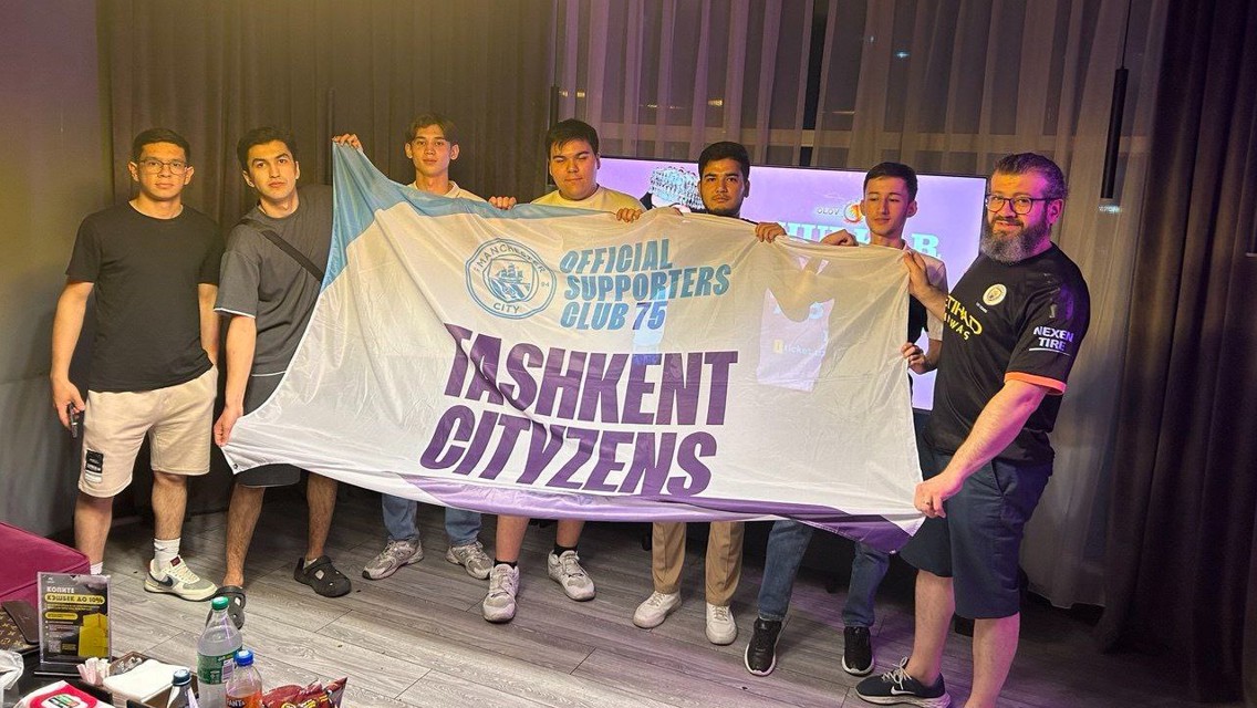Group holding a 'Tashkent Cityzens' banner, indicating official supporters club affiliation with Manchester City.