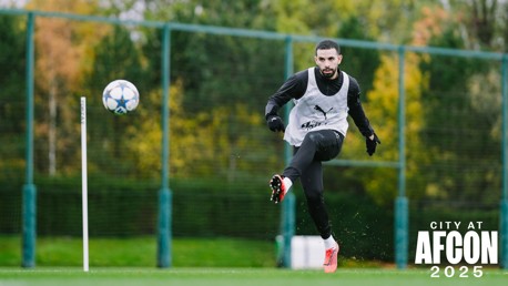 A football player training, kicking a ball with a bib on, and the text 'CITY AT AFCON 2025' seen on the image.