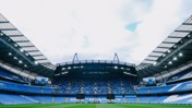Panoramic view of an empty stadium with blue seats and large screens under a cloudy sky.