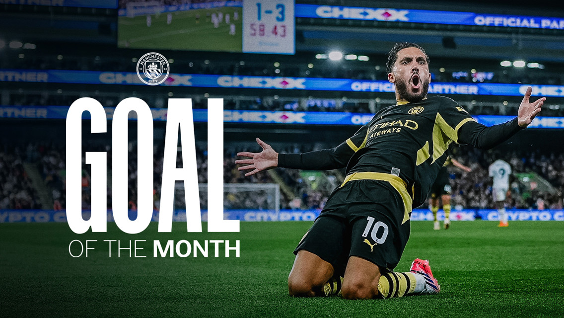 A soccer player celebrates a goal on the field. 'Goal of the Month' is prominently displayed alongside the Manchester City logo. The scoreboard in the background shows a scoreline of 1-3.