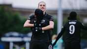 Two female football players embracing on the field, celebrating a moment in what appears to be a Manchester City Women's team match. One player's back shows the name 'Bunny' and number '9'.
