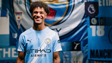 A Manchester City player wearing the 2023 home kit, featuring the Manchester City badge and Etihad Airways logo.