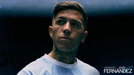 Individual in a light blue shirt with tattoos on neck and a serious expression, dark background with text: 'Welcome to City Enzo Fernández'.