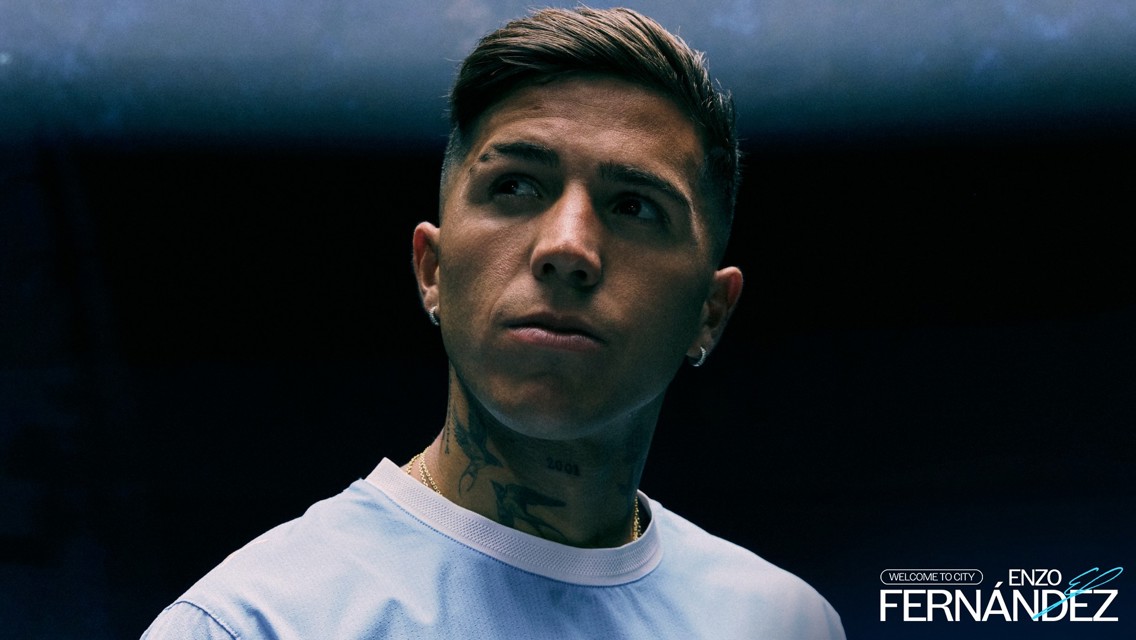 Individual in a light blue shirt with tattoos on neck and a serious expression, dark background with text: 'Welcome to City Enzo Fernández'.